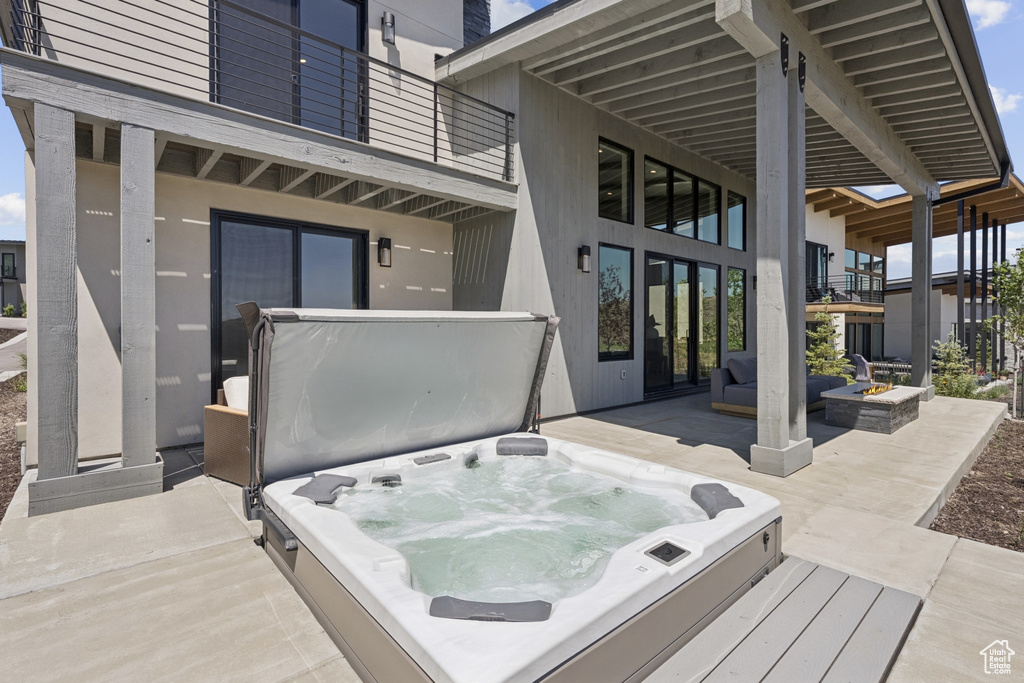 Wooden deck featuring a covered hot tub, an outdoor fire pit, and a patio