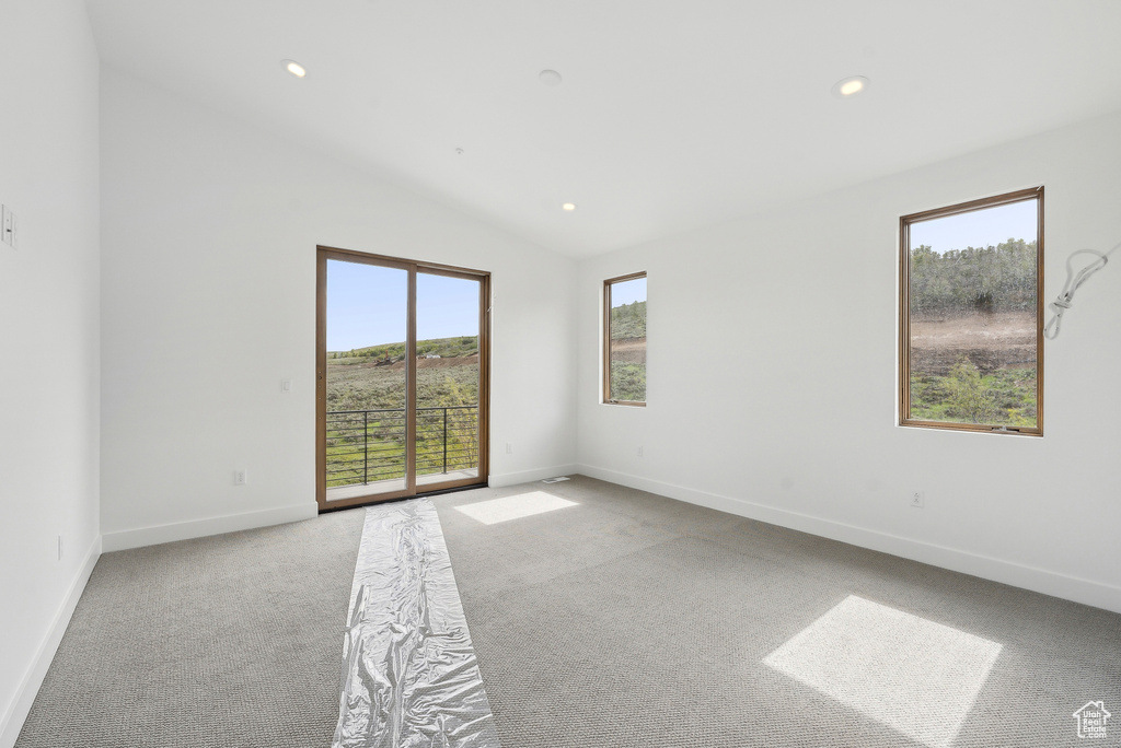 Carpeted empty room featuring healthy amount of natural light, baseboards, vaulted ceiling, and recessed lighting