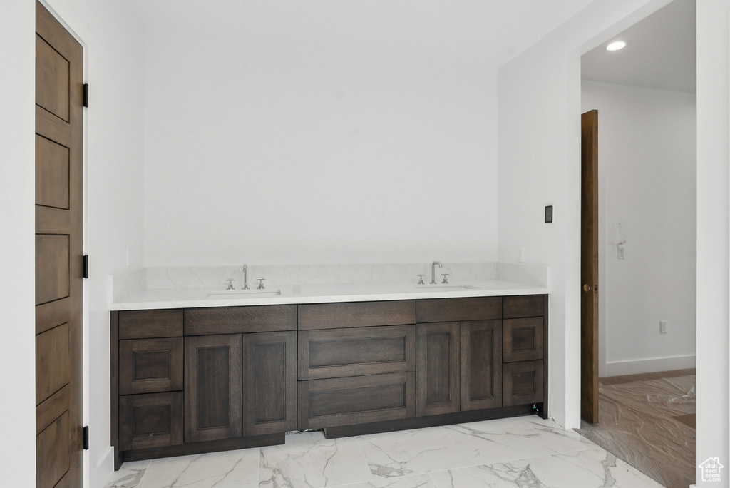 Bathroom with marble look tiles, recessed lighting, double vanity, and baseboards