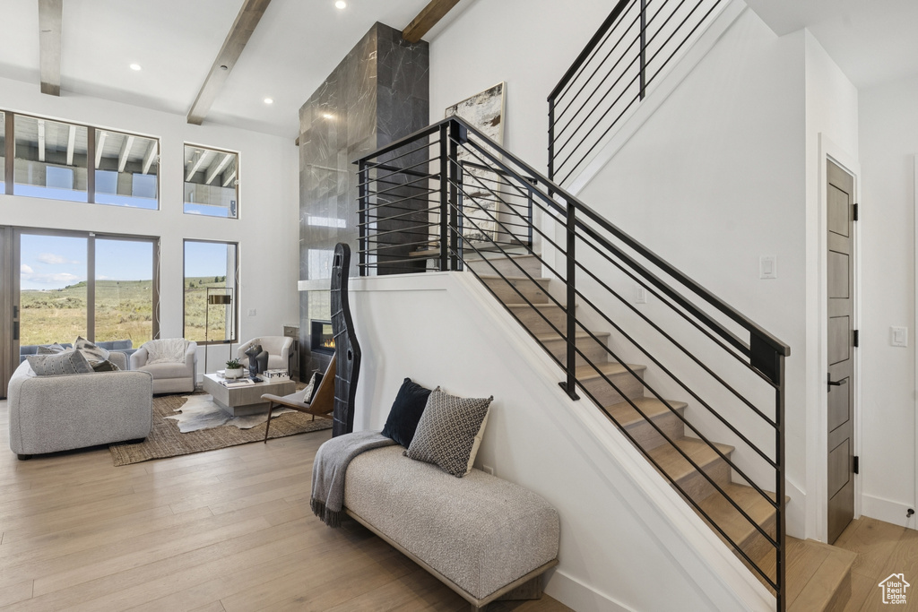 Stairway featuring a towering ceiling, beamed ceiling, wood finished floors, and recessed lighting