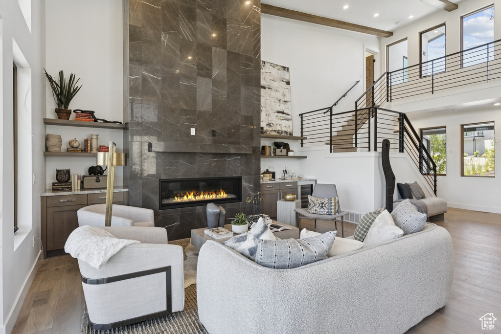 Living area with stairway, wood finished floors, a fireplace, recessed lighting, and a high ceiling