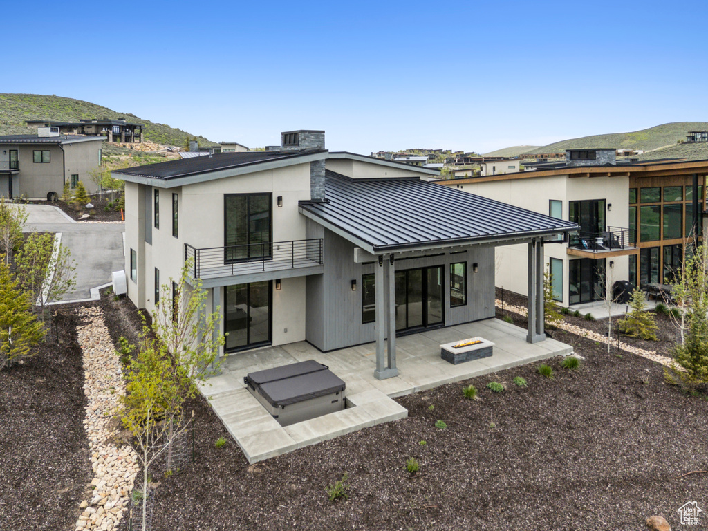 Rear view of property featuring a balcony, a standing seam roof, a patio, metal roof, and a mountain view