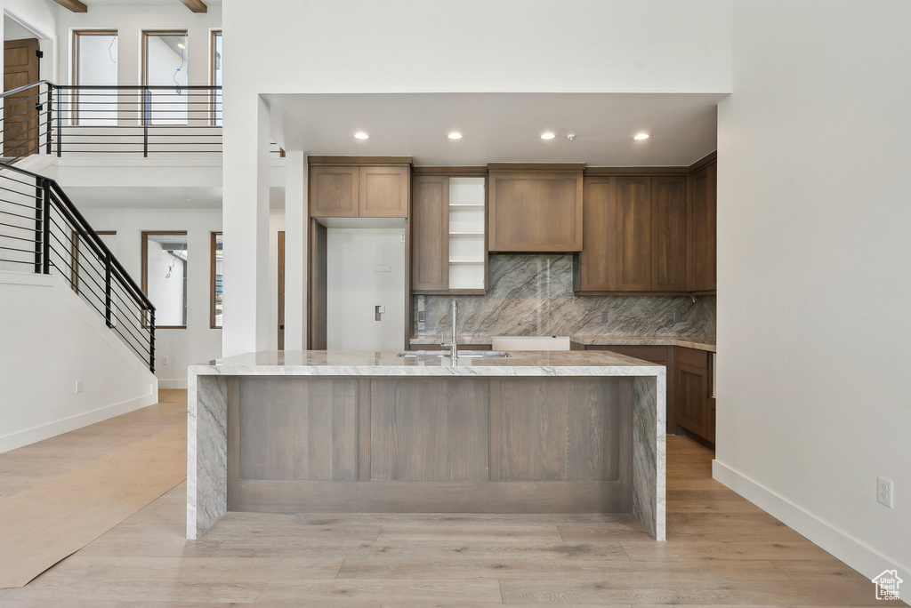 Kitchen featuring a sink, tasteful backsplash, light stone countertops, baseboards, and recessed lighting