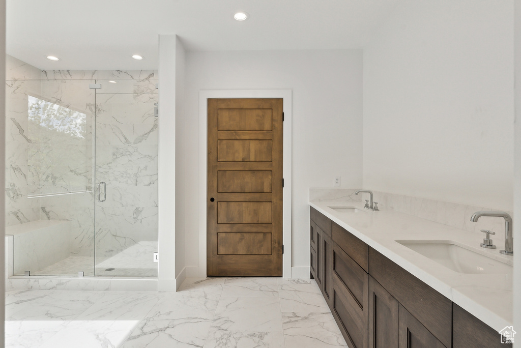 Bathroom with marble finish flooring, recessed lighting, a marble finish shower, double vanity, and baseboards