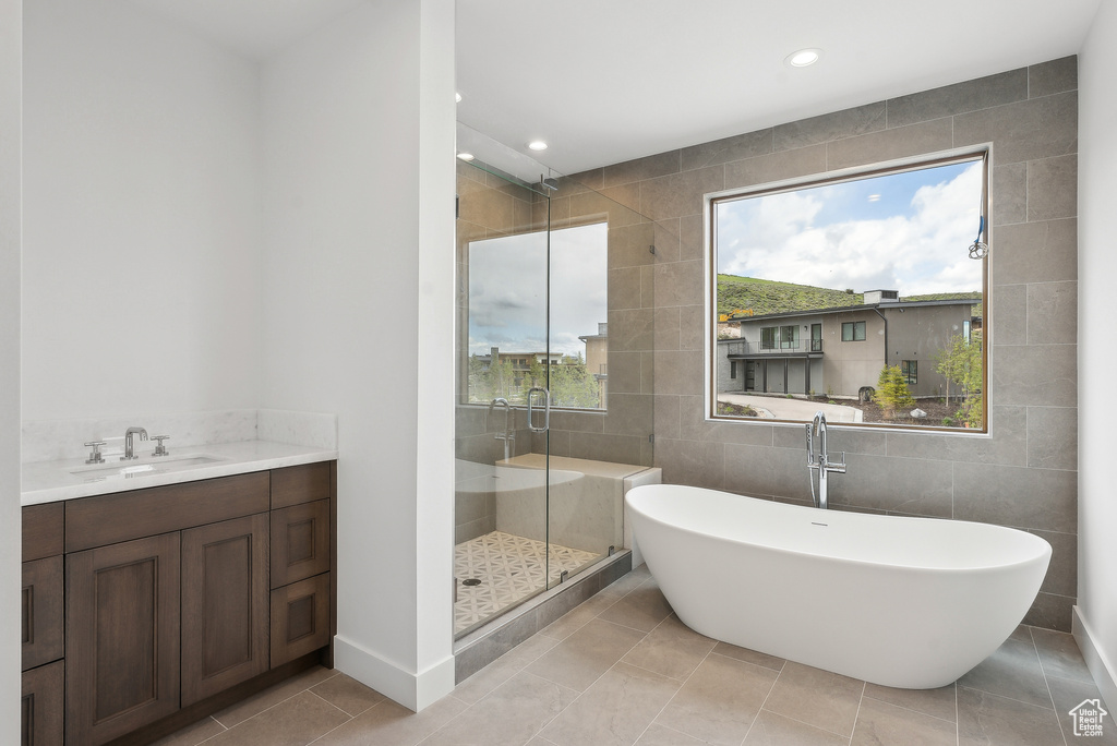 Full bathroom with tile walls, a shower stall, recessed lighting, a soaking tub, and vanity