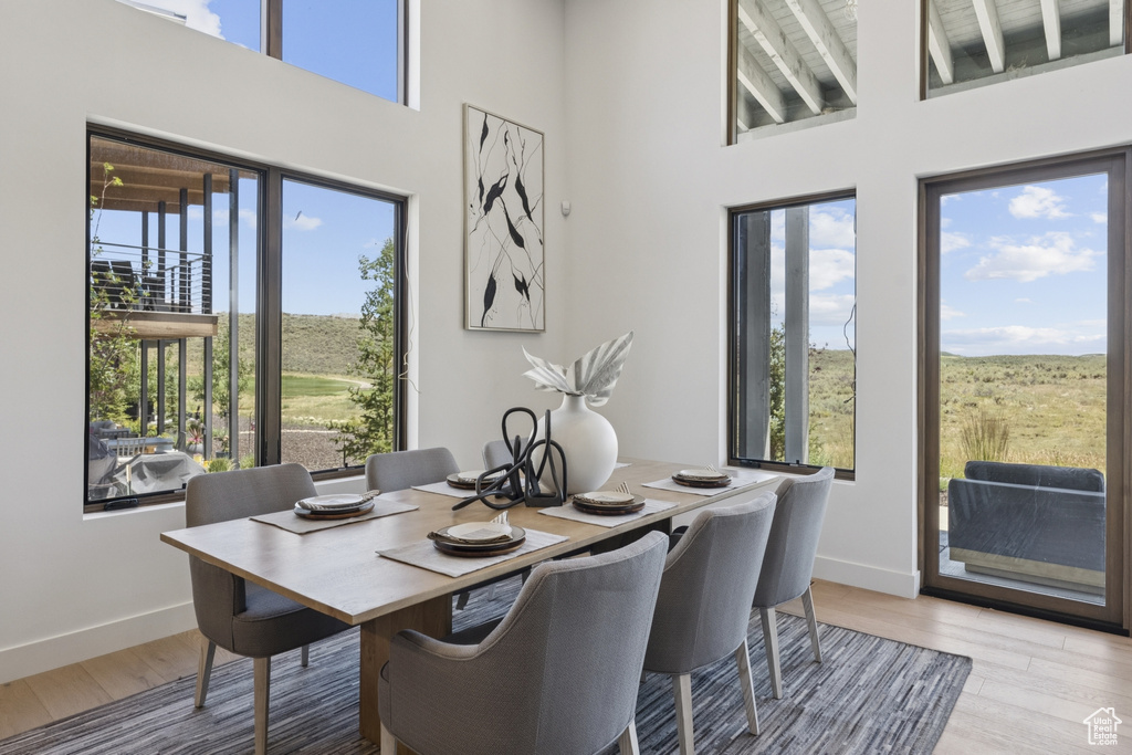 Dining room with light wood-style flooring and a towering ceiling