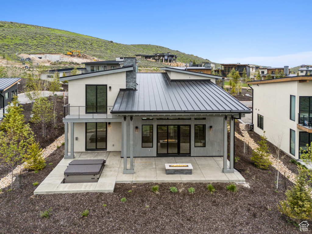 Back of house with a standing seam roof, a balcony, a mountain view, and metal roof