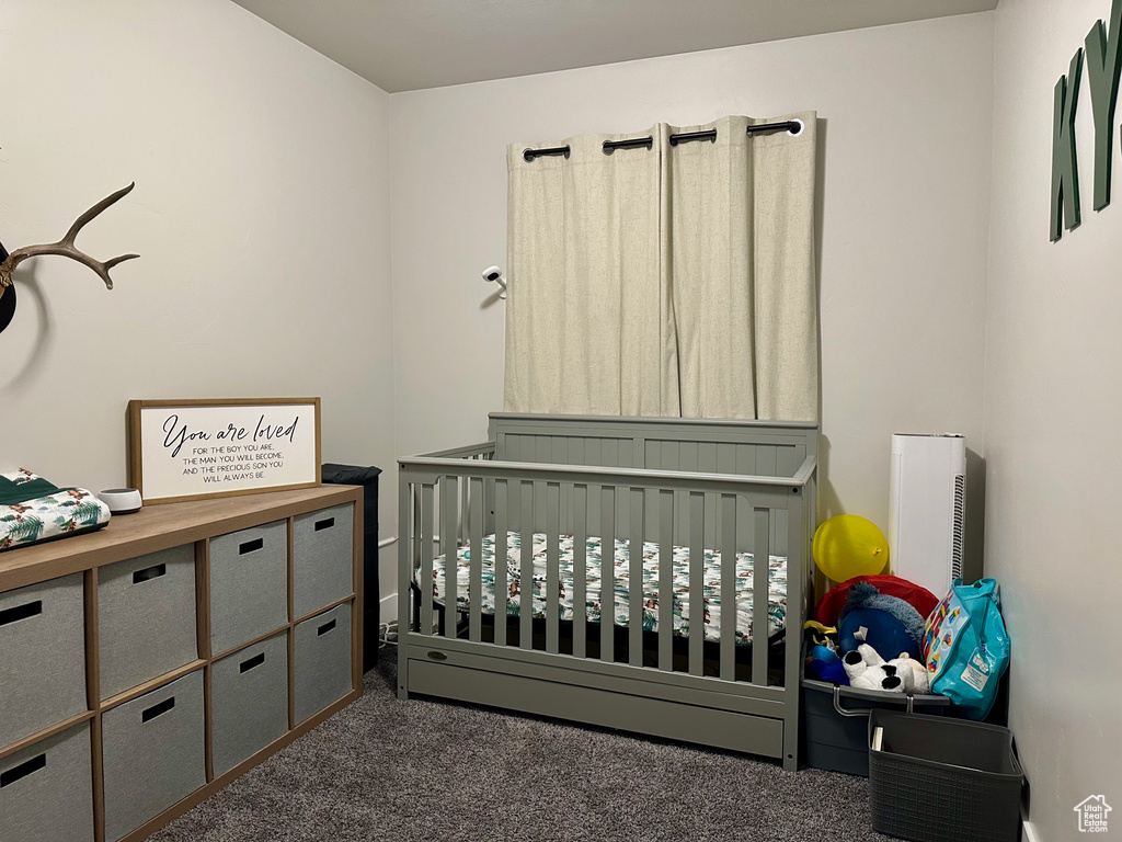 Bedroom with a nursery area and dark colored carpet