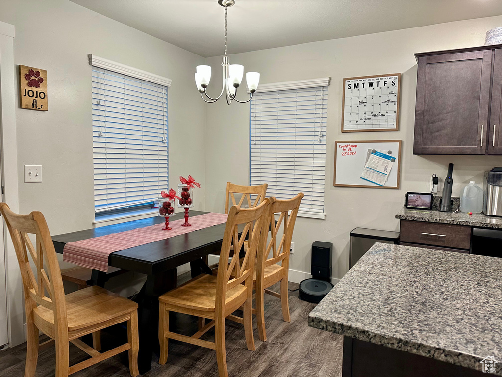 Dining room with dark wood-type flooring and a chandelier