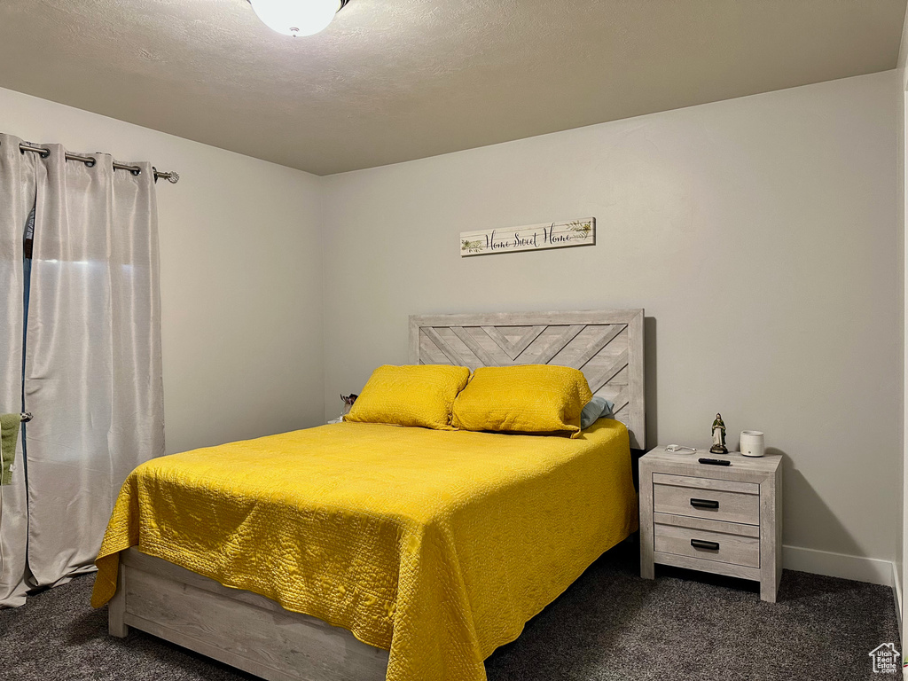 Bedroom with dark carpet and a textured ceiling