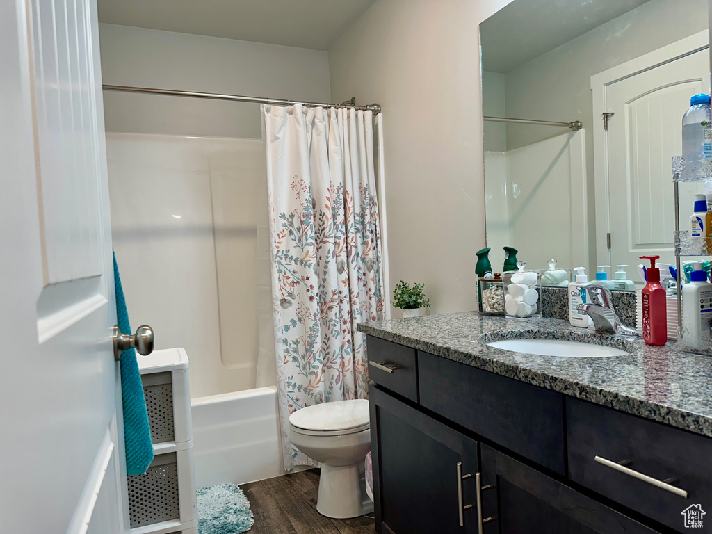 Full bathroom featuring shower / tub combo, vanity, hardwood / wood-style flooring, and toilet