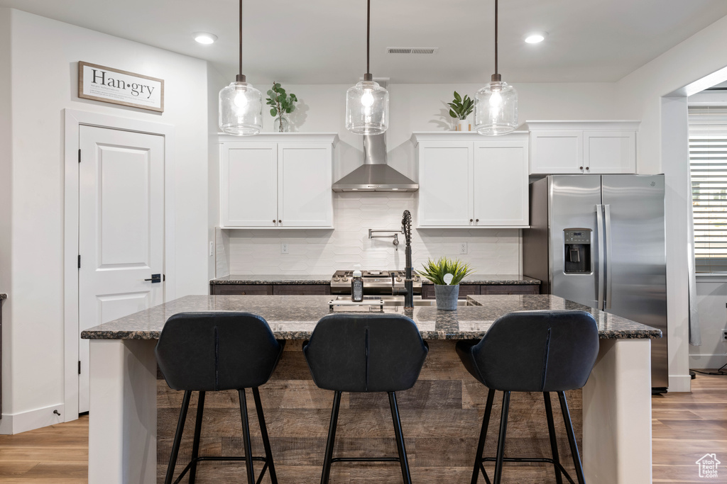Kitchen featuring a center island with sink, white cabinetry, and light hardwood / wood-style flooring