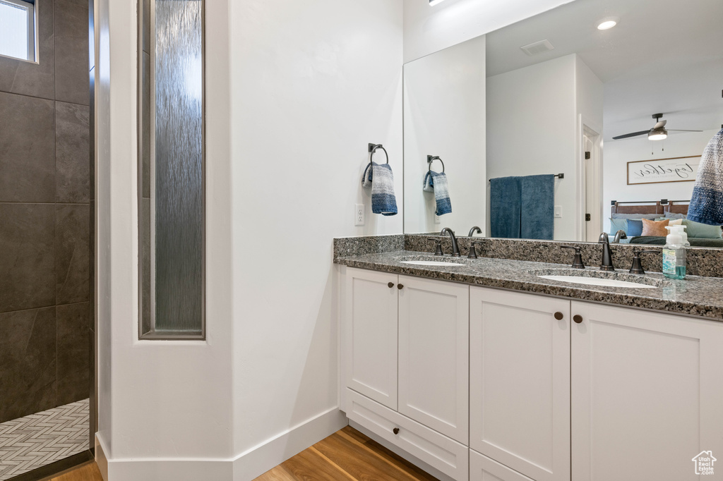 Bathroom with a tile shower, ceiling fan, hardwood / wood-style floors, and vanity