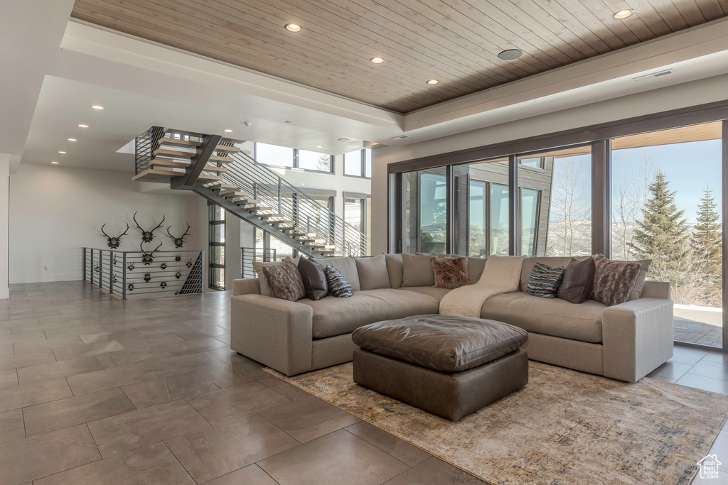 Living room featuring stairway, wooden ceiling, recessed lighting, and a raised ceiling
