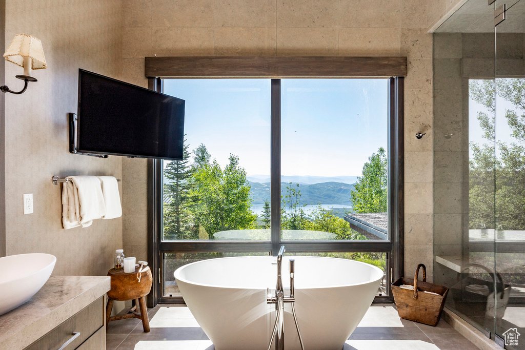 Full bathroom featuring a freestanding bath, tile patterned flooring, and vanity