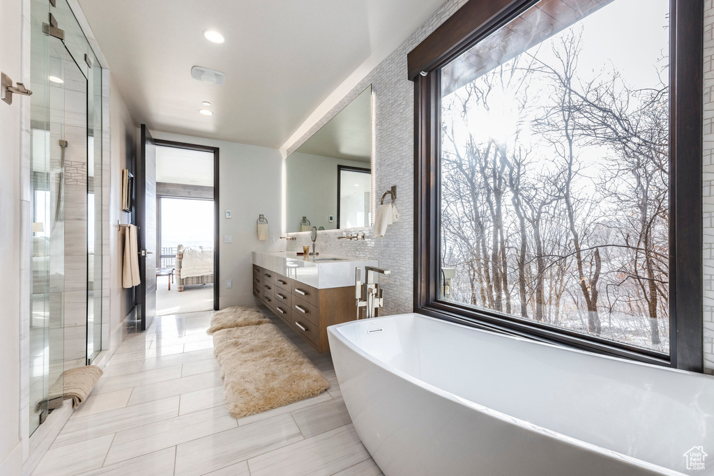 Full bathroom featuring vanity, a freestanding bath, a shower stall, tile patterned floors, and recessed lighting