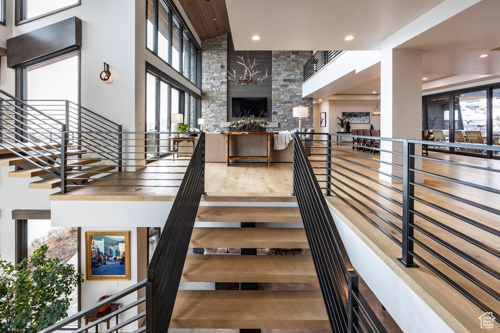 Stairway with a high ceiling, a fireplace, recessed lighting, and wood finished floors