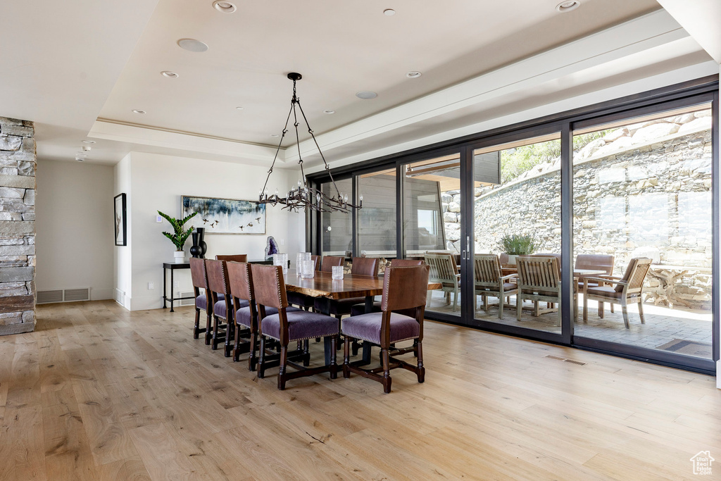 Dining area featuring light wood-type flooring, a raised ceiling, and recessed lighting