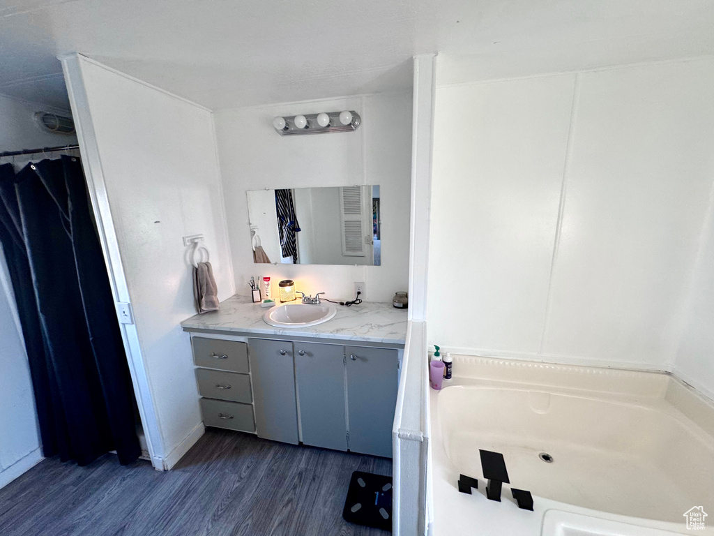 Bathroom with a washtub, wood-type flooring, and vanity