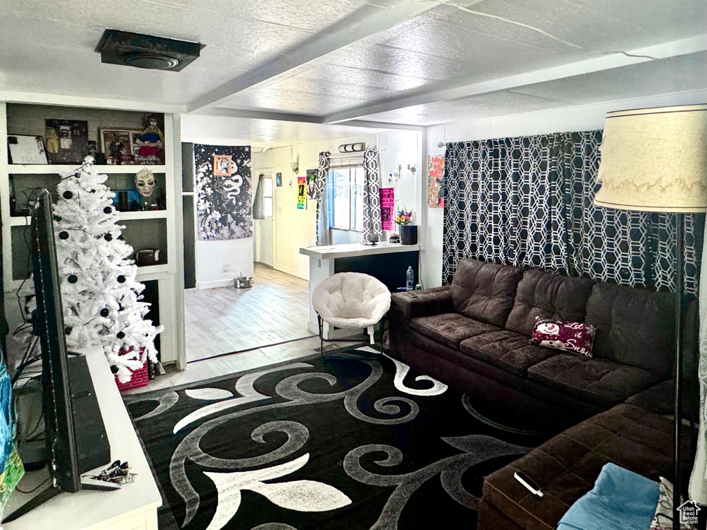 Living room with beamed ceiling, hardwood / wood-style floors, and a textured ceiling