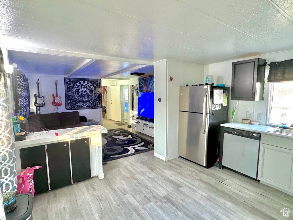 Kitchen featuring a textured ceiling, sink, stainless steel appliances, and light hardwood / wood-style flooring