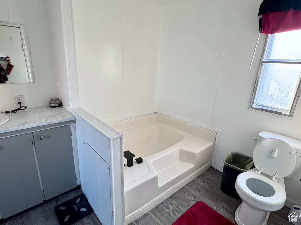 Bathroom with a bathing tub, hardwood / wood-style floors, vanity, and toilet