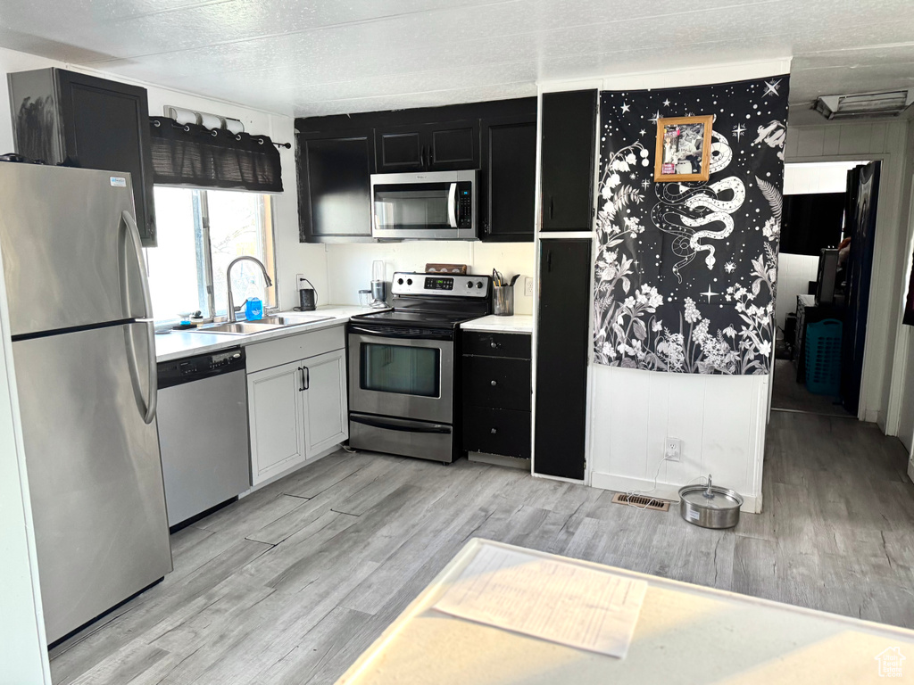 Kitchen featuring sink, stainless steel appliances, a textured ceiling, and light hardwood / wood-style floors