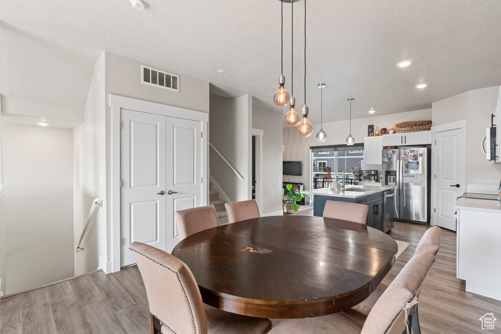 Dining room featuring sink, light wood-type flooring, and a textured ceiling