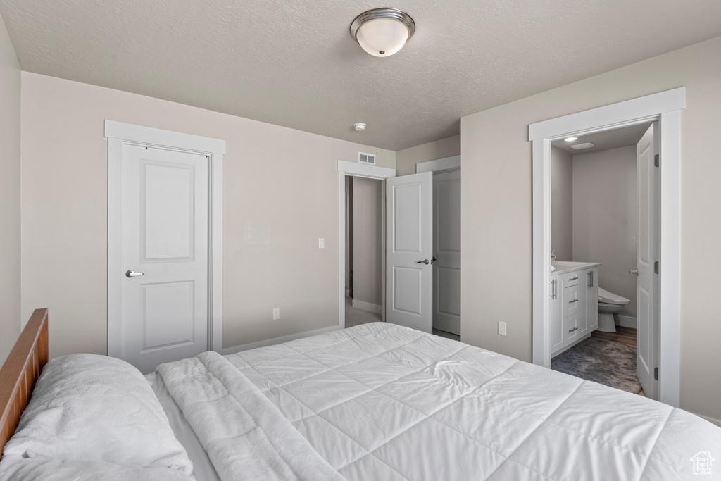 Bedroom featuring ensuite bath, a closet, and a textured ceiling