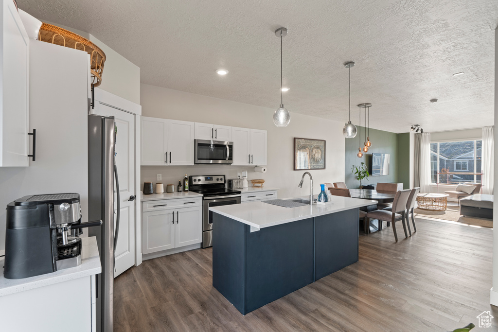 Kitchen featuring sink, an island with sink, pendant lighting, white cabinets, and appliances with stainless steel finishes