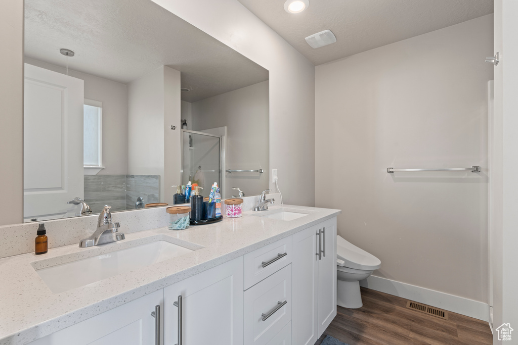 Bathroom with hardwood / wood-style floors, vanity, toilet, and an enclosed shower