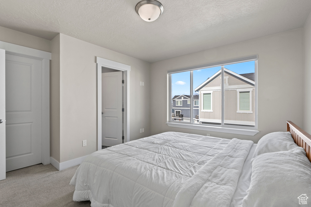 Bedroom with a textured ceiling and light colored carpet