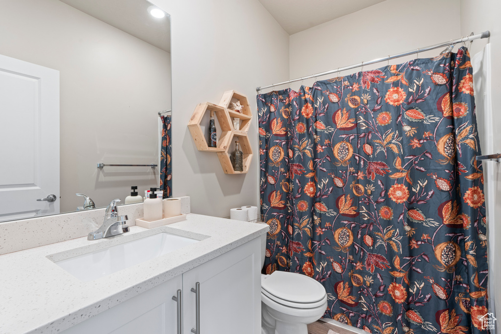Bathroom featuring a shower with curtain, vanity, and toilet