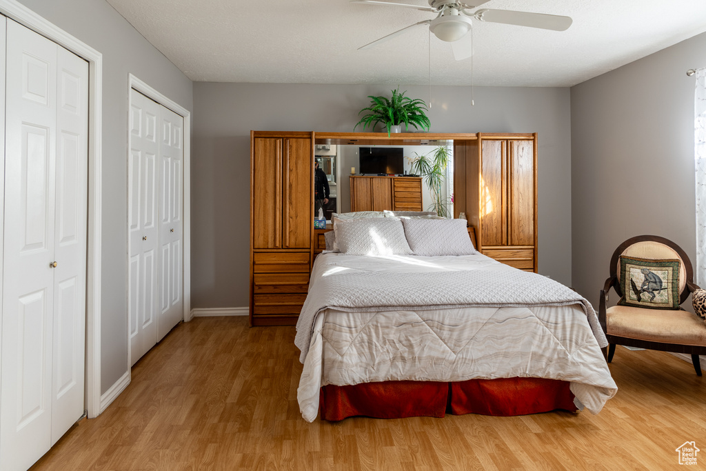 Bedroom featuring ceiling fan, light hardwood / wood-style floors, and two closets