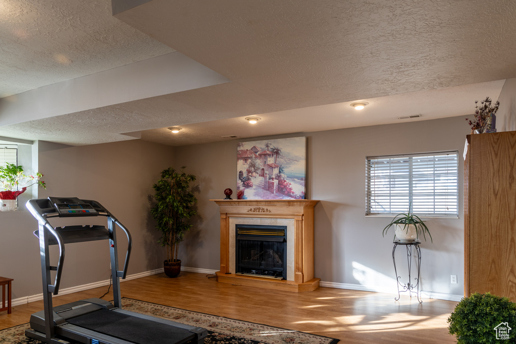 Exercise room with a textured ceiling and hardwood / wood-style flooring