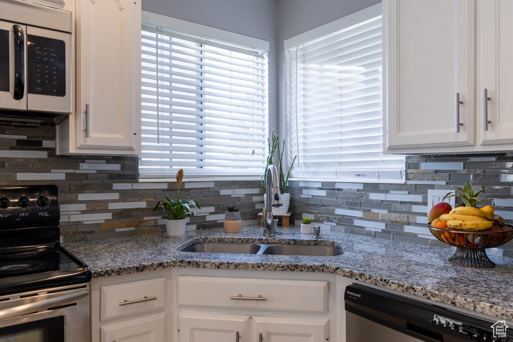 Kitchen featuring dishwasher, white cabinetry, black electric range oven, and sink