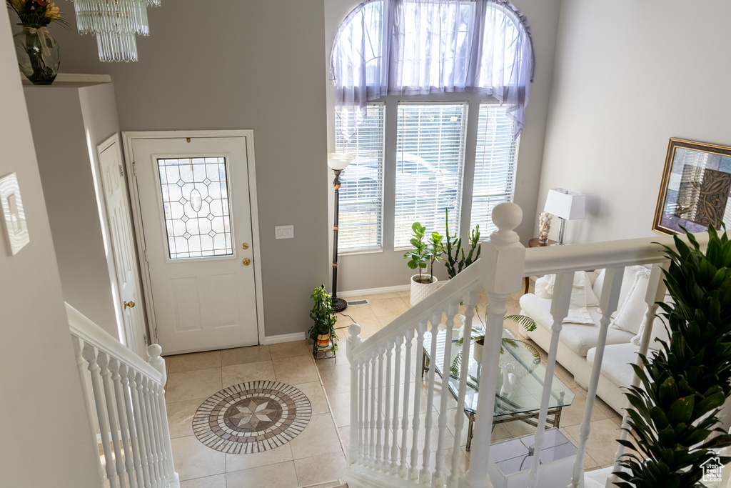Entrance foyer with a healthy amount of sunlight, light tile patterned flooring, and a chandelier