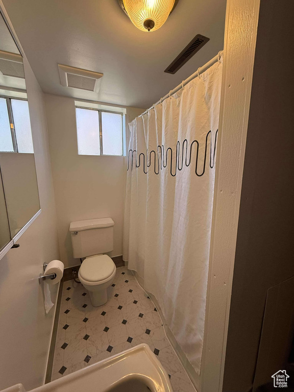 Bathroom with a shower with shower curtain and toilet