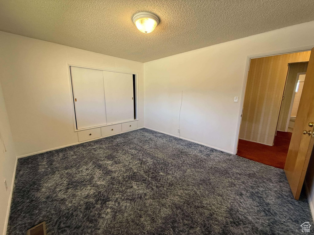 Unfurnished bedroom with carpet flooring, a textured ceiling, and a closet