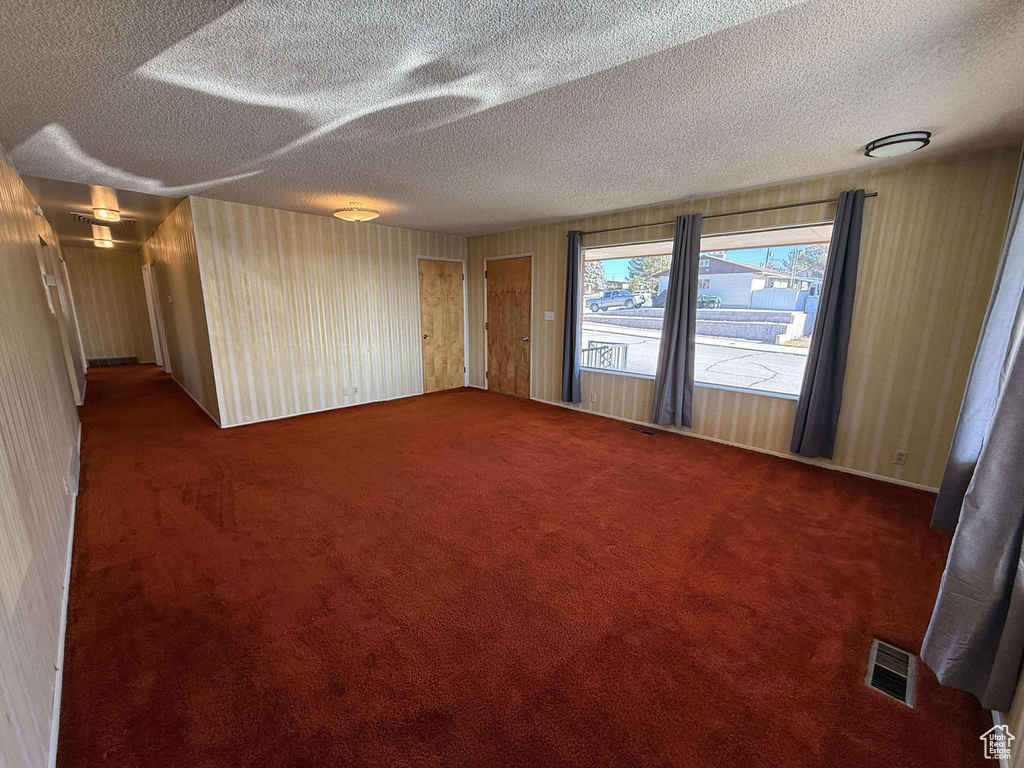 Spare room featuring dark carpet and a textured ceiling