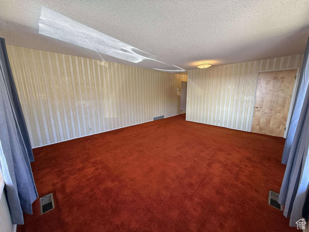 Carpeted empty room with a textured ceiling