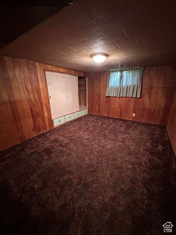 Carpeted spare room with wooden walls