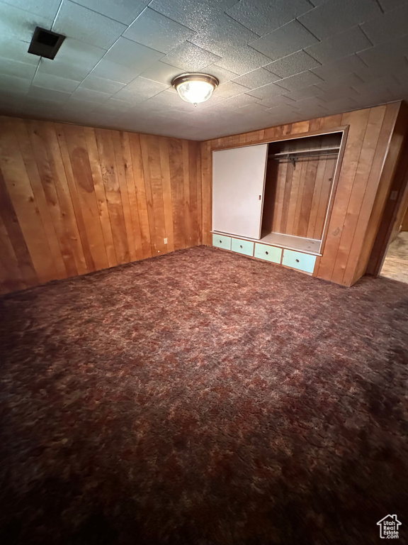 Unfurnished bedroom with wooden walls and carpet