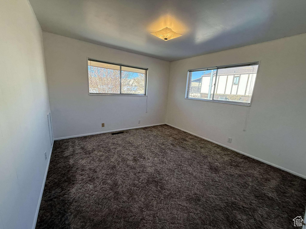 Spare room featuring dark carpet