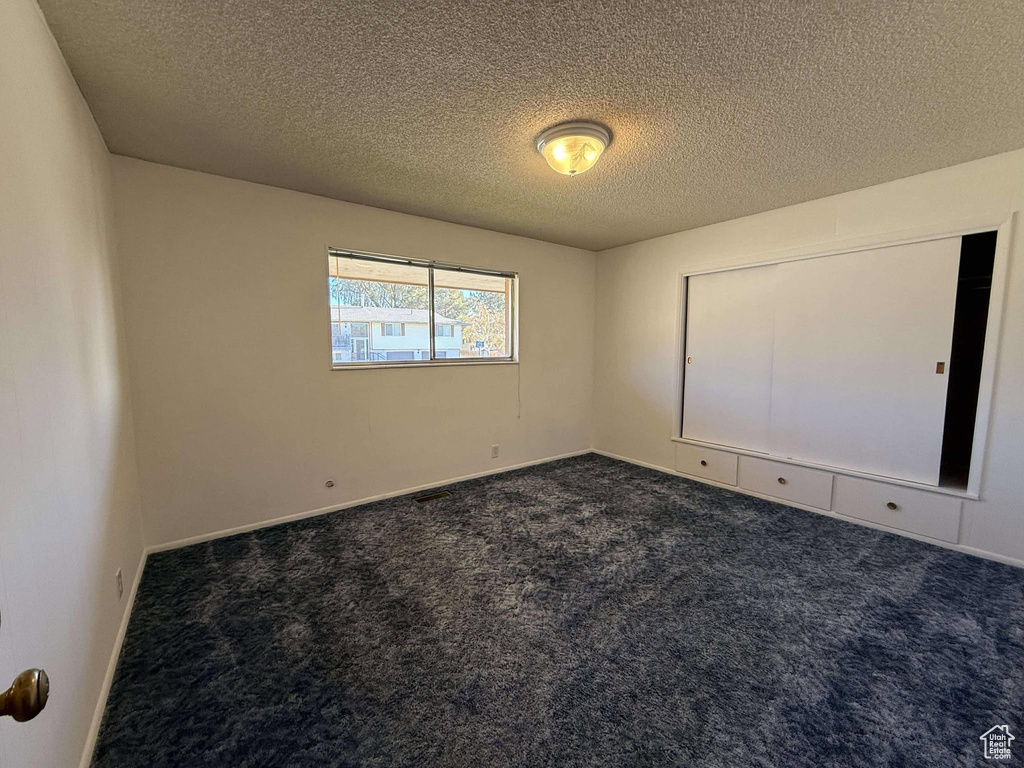 Carpeted spare room with a textured ceiling