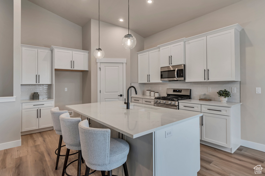 Kitchen with white cabinets, tasteful backsplash, a breakfast bar, and appliances with stainless steel finishes