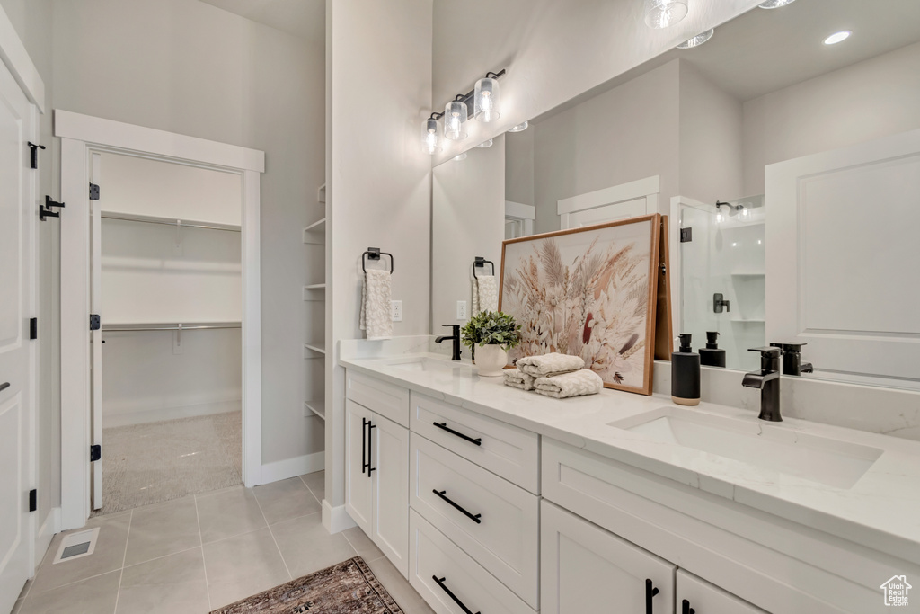 Bathroom featuring a walk in closet, a walk in shower, double vanity, and a sink