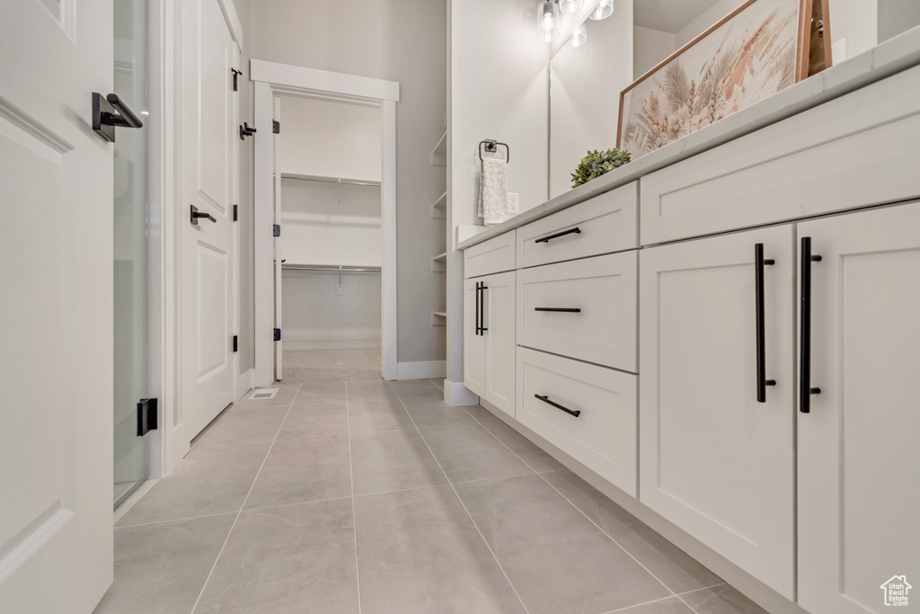 Bathroom featuring tile patterned floors, vanity, and a walk in closet