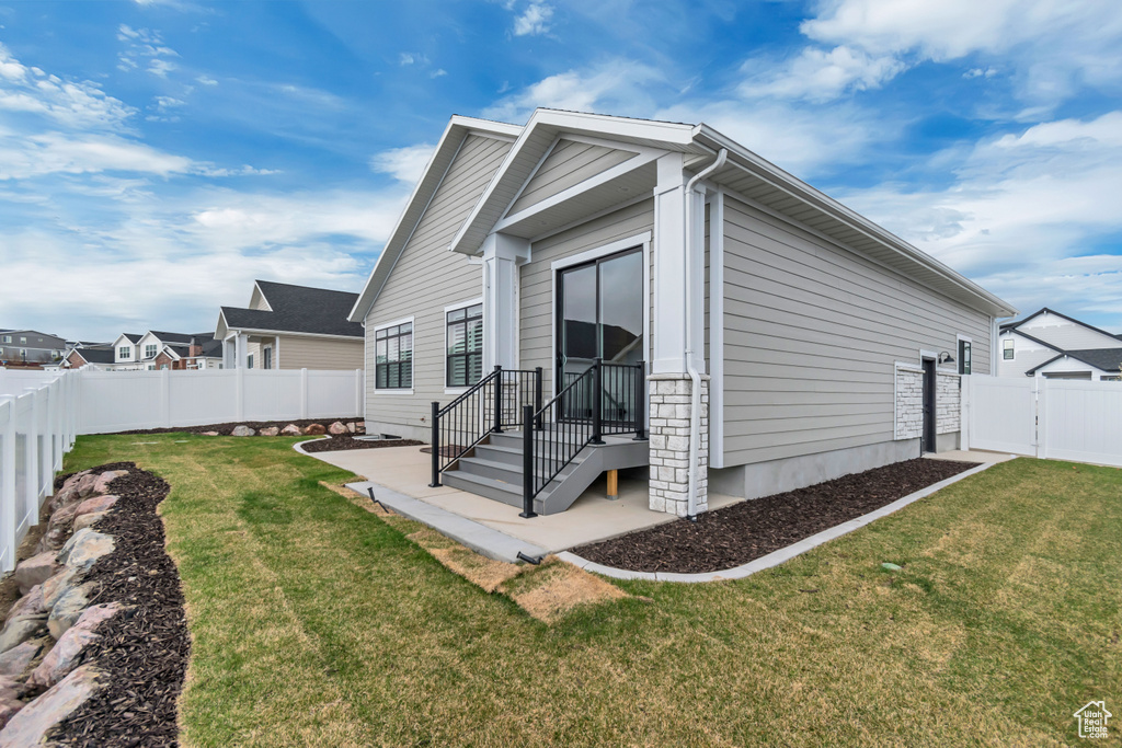 View of property exterior featuring a lawn, a fenced backyard, and a patio area