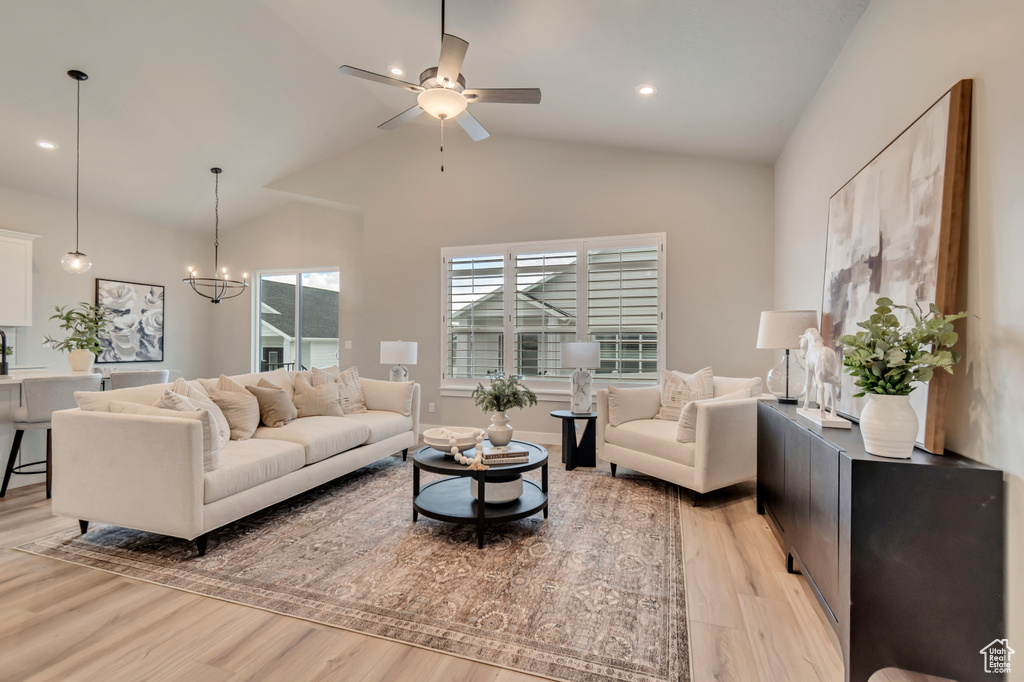 Living room with recessed lighting, ceiling fan with notable chandelier, light wood-style flooring, and high vaulted ceiling